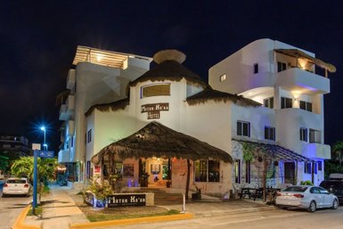 Das Matan K'aan Hotel präsentiert sich mit einem einladenden Eingangsbereich und einem strohgedeckten Dach in der Nacht.