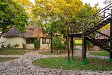 Eine malerische Landschaft mit strohgedeckten Hütten, umgeben von üppigem Grün und einem geschwungenen Steinweg.