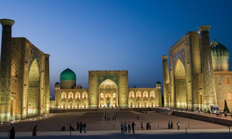 Die beeindruckende Architektur der Registan in Samarkand erstrahlt in warmem Licht, während Menschen die Szenerie genießen.