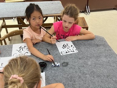 Kinder üben chinesische Kalligrafie auf Papier – China Reise mit Kindern