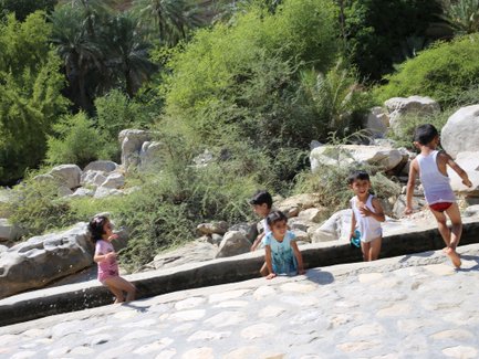 Kinder in Oman spielen im Wasserkanal - Oman Reise mit Kindern