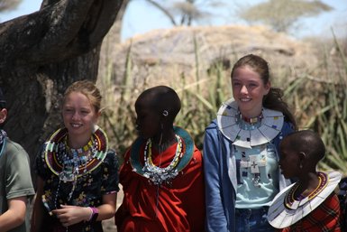 Zwei Schwestern mit Massai in traditionellem Schmuck – Tansania Reise mit Kindern