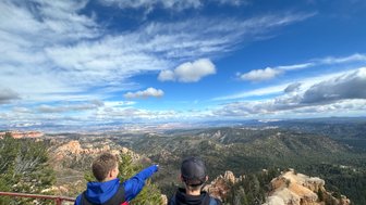 Zwei Personen stehen an einem Aussichtspunkt und blicken auf die beeindruckende Landschaft des Bryce Canyon Nationalparks.