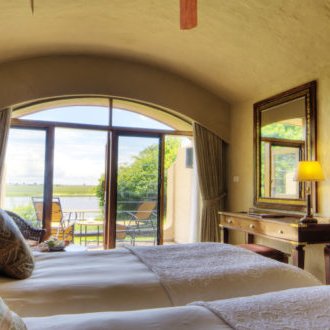 Ein gemütliches Zimmer mit zwei Einzelbetten, das durch große Fenster auf eine grüne Landschaft blickt.