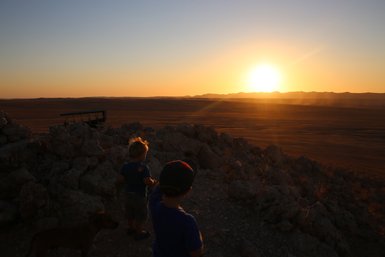 Zwei Kinder schauen neugierig in die weite Wüstenlandschaft - Namibia Urlaub mit Kindern