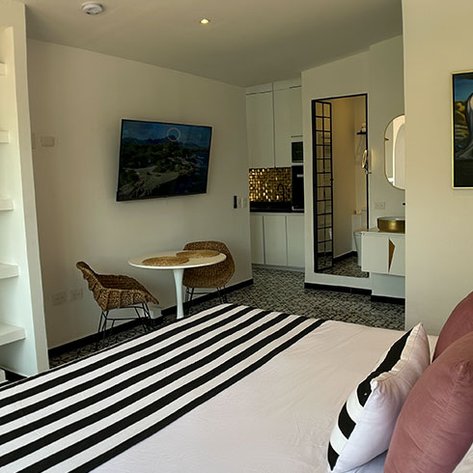 Ein modernes Hotelzimmer mit einem großen Bett, gestreiften Bettlaken und einem gemütlichen Sitzbereich mit einem Tisch.