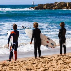 Drei Kinder warten auf die nächste Welle zum surfen