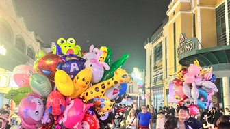Bunte Luftballons in verschiedenen Formen und Farben werden von Verkäufern auf einer belebten Straße in Hanoi angeboten.