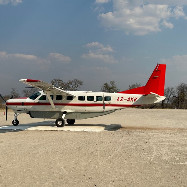 Das Flugzeug A2-AKK ist auf einer staubigen Landebahn geparkt, während die Sonne über der afrikanischen Landschaft scheint.
