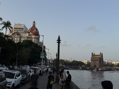 Die lebhafte Uferpromenade in Mumbai zeigt Menschen, die entlang des Wassers spazieren, mit dem Gateway of India im Hintergrund.