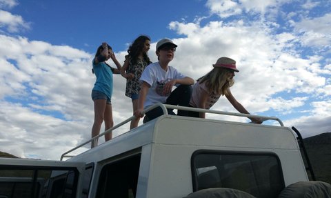 Vier Kinder stehen auf einem Jeep Dach und schauen in die Ferne - Namibia Familienurlaub