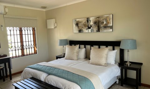 Ein gemütliches Schlafzimmer mit einem großen Bett, dekorativen Kissen und einem sanften Licht von einer Tischlampe.