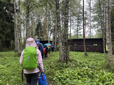 Eine Gruppe von Menschen wandert durch einen bewaldeten Bereich, um ein Beobachtungsgebäude zu erreichen.