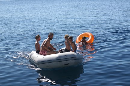 Eine Gruppe von Kindern und einem Erwachsenen fährt in einem Gummiboot auf dem ruhigen blauen Wasser des Meeres.