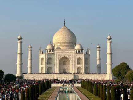 Das majestätische Taj Mahal strahlt im Sonnenlicht, umgeben von einer großen Menschenmenge und gepflegten Gärten.