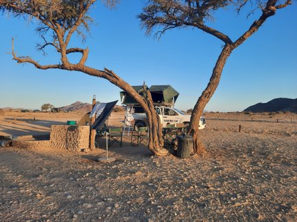 Ein Jeep mit Dachzelt steht neben einem aufgebauten Camp - Namibia mit Jugendlichen