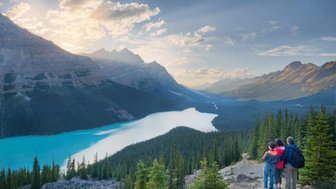 Ein Paar und ein Kind stehen auf einem Aussichtspunkt und bewundern die atemberaubende Landschaft des Icefield Parkway.