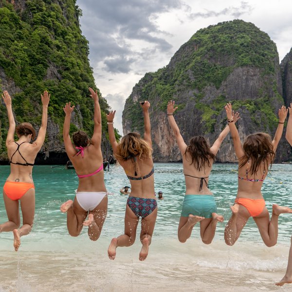 Mädchen springen lachend am Strand entlang der tropischen Küste – Thailand mit Kindern