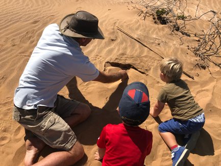 Ein Mann und zwei Kinder sitzen im Sand - Namibia Familienurlaub