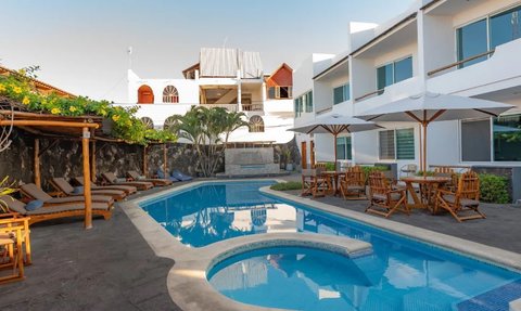 Ein einladender Poolbereich mit Liegen und Sonnenschirmen, umgeben von modernen Gebäuden und üppiger Vegetation.