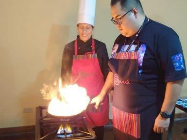 Ein Kochkurs in Lima, wo ein Mann und eine Frau mit einem brennenden Wok kochen, während sie konzentriert zuschauen.