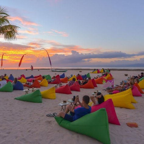 Bunte Sitzsäcke am Strand bieten eine entspannte Atmosphäre, während die Sonne hinter dem Horizont untergeht.
