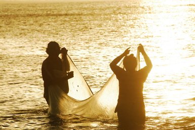 Fischer im Wasser während der Sonnenaufgang den Himmel färbt – Nicaragua Reise mit Kindern