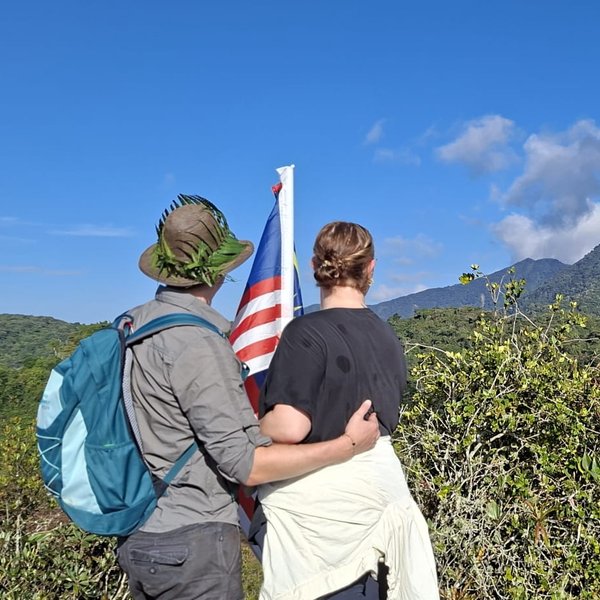 Teenager mit malaysischer Flagge und For Family Reisen Rucksack genießen den Ausblick nach der Coral Hill-Wanderung in den Cameron Highlands - Malaysia Familienreise
