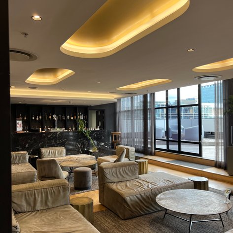 Ein eleganter Lobbybereich mit bequemen, hellen Sofas und einem stilvollen Tisch, umgeben von großen Fenstern.