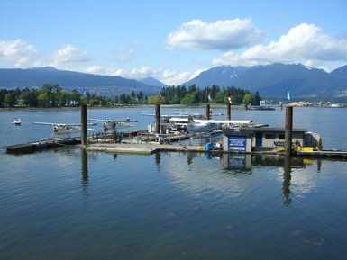 Ein ruhiger Hafen mit Wasserflugzeugen, umgeben von Bergen und einer klaren blauen Himmel, spiegelt die friedliche Atmosphäre wider.