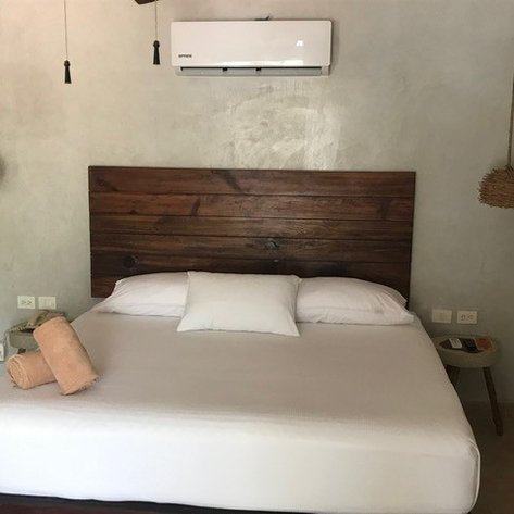 Ein gemütliches Schlafzimmer mit einem großen Bett, Holzdetails und einer Klimaanlage an der Wand.
