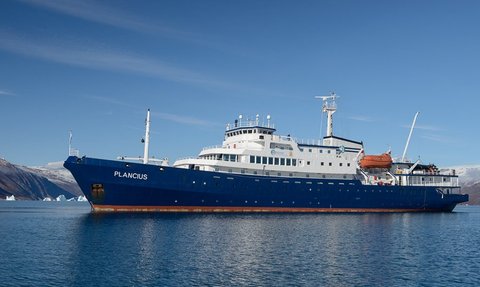 Das Forschungsschiff Plancius liegt ruhig im Wasser, umgeben von majestätischen Bergen und Eisbergen im Hintergrund.