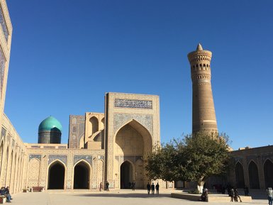 Der Po-i-Kalyan-Komplex in Buchara zeigt beeindruckende Architektur mit einem hohen Minarett und einer blauen Kuppel.