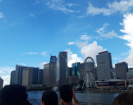 Die Skyline von Miami wird von einem Boot aus betrachtet, während Menschen am Rand des Bootes sitzen und die Aussicht genießen.
