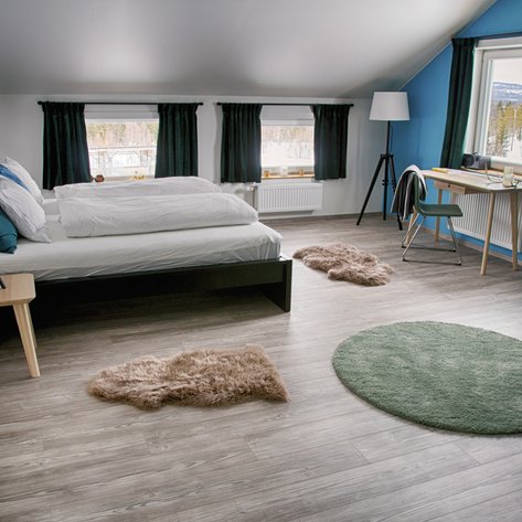 Ein modernes Schlafzimmer mit einem großen Bett, weichen Teppichen und einem Schreibtisch, der zum Arbeiten einlädt.