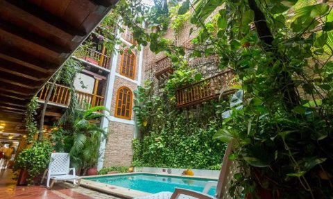 Ein ruhiger Innenhof mit einem Pool, umgeben von üppigem Grün und historischen Ziegelwänden, lädt zur Entspannung ein.