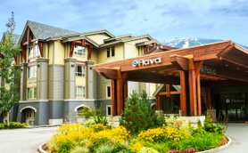 Das Aava Hotel in Whistler zeigt eine moderne Architektur mit Holzverkleidung und großen Fenstern, umgeben von bunten Blumen.