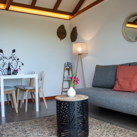 Ein stilvolles Wohnzimmer mit einem grauen Sofa, einem runden Tisch und einer modernen Stehlampe, die eine gemütliche Atmosphäre schafft.