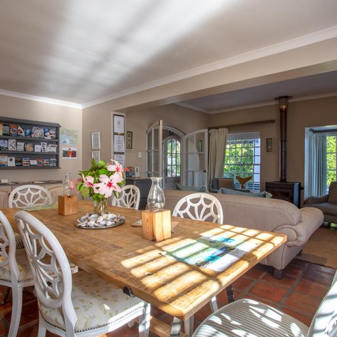 Ein einladender Empfangsbereich mit einem Holztisch, umgeben von eleganten Stühlen und einer Vase mit frischen Blumen.