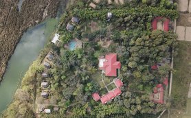 Eine Luftaufnahme eines malerischen Lodges mit roten Dächern, umgeben von üppigem Grün und einem ruhigen Gewässer.