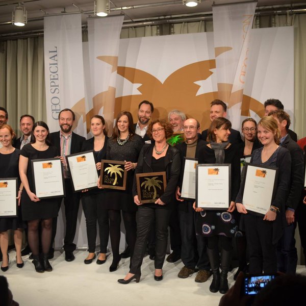 Eine Gruppe von Menschen steht auf einer Bühne und hält Auszeichnungen in den Händen, um ihre Erfolge zu feiern.