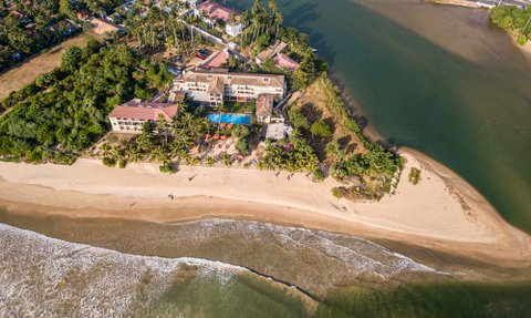 Ein Blick auf das Mirissa Mandara Resort, umgeben von Palmen und dem ruhigen Wasser eines Flusses, der ins Meer mündet.