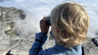 Junge schaut mit Fernglas über die Landschaft vom Tafelberg – Südafrika mit Kindern