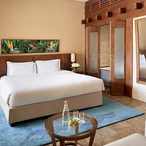 Ein elegantes Hotelzimmer mit einem großen Bett, Holzdetails und einem gemütlichen Sitzbereich, ideal für Entspannung.