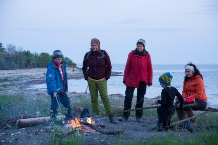 Eine Familie steht um ein Lagerfeuer, während die Kinder Marshmallows grillen