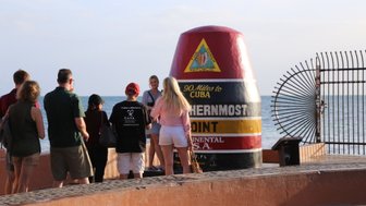 Eine Gruppe von Touristen steht am Southernmost Point in den USA, während sie den berühmten Marker bewundern.