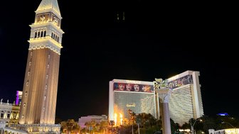 Der beleuchtete Glockenturm des Venetian Hotels erhebt sich majestätisch über die belebte Las Vegas Boulevard bei Nacht.