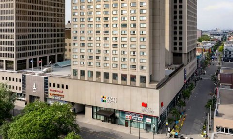 Ein modernes Hotelgebäude mit großen Fenstern und einem klaren, strukturierten Design in der Innenstadt von Montreal.