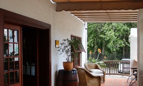 Der Eingangsbereich des Noordhoek Village Hotels zeigt eine einladende Atmosphäre mit Pflanzen und einem gemütlichen Sessel.