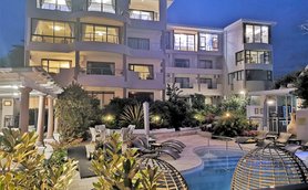 Ein elegantes Boutique-Hotel mit einem einladenden Poolbereich, umgeben von üppigem Grün und stilvollen Liegen.